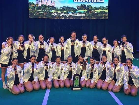 team all wearing white jackets and biting medals